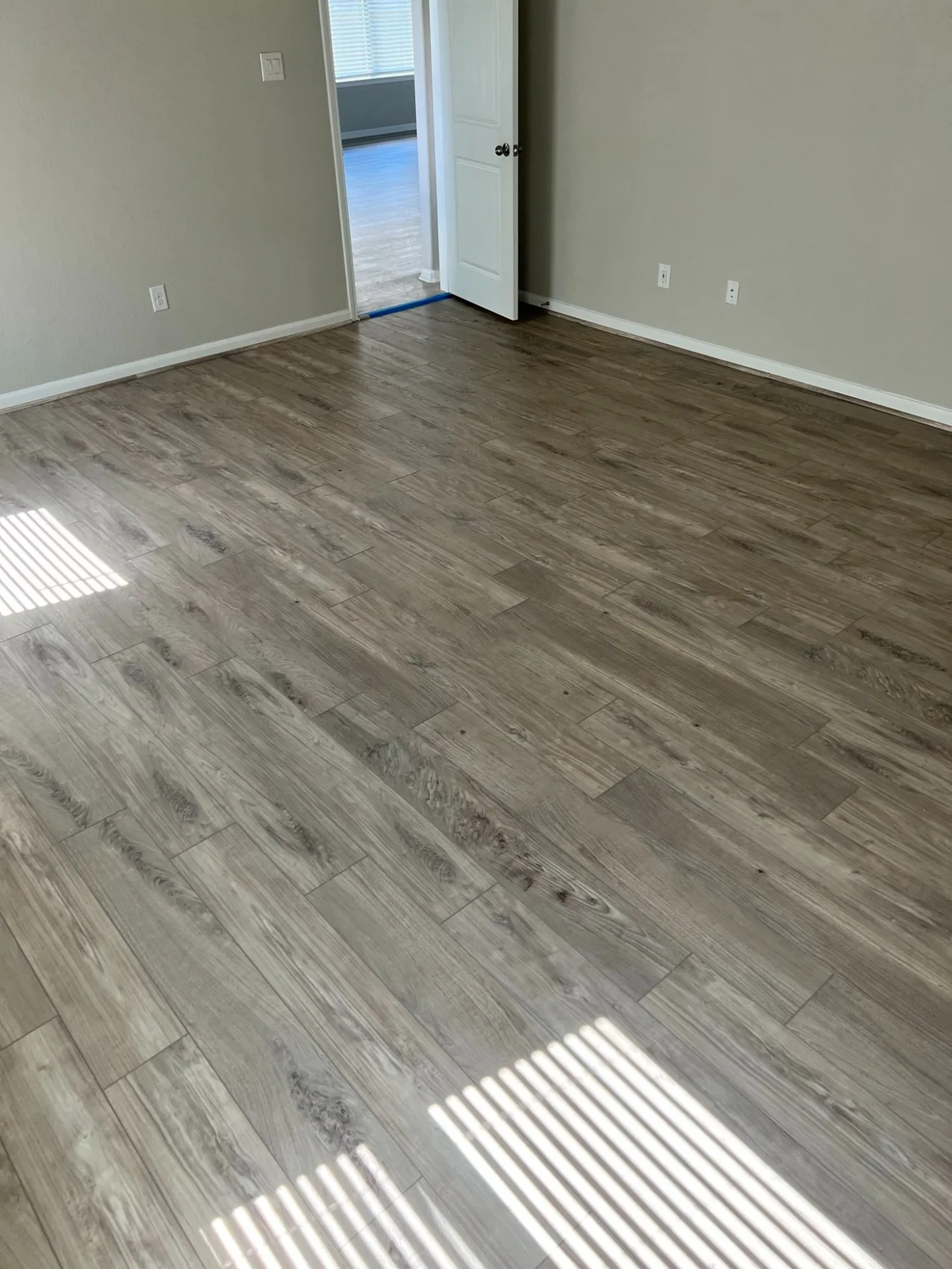 Classic gray vinyl plank running through an entry and hallway to a back door