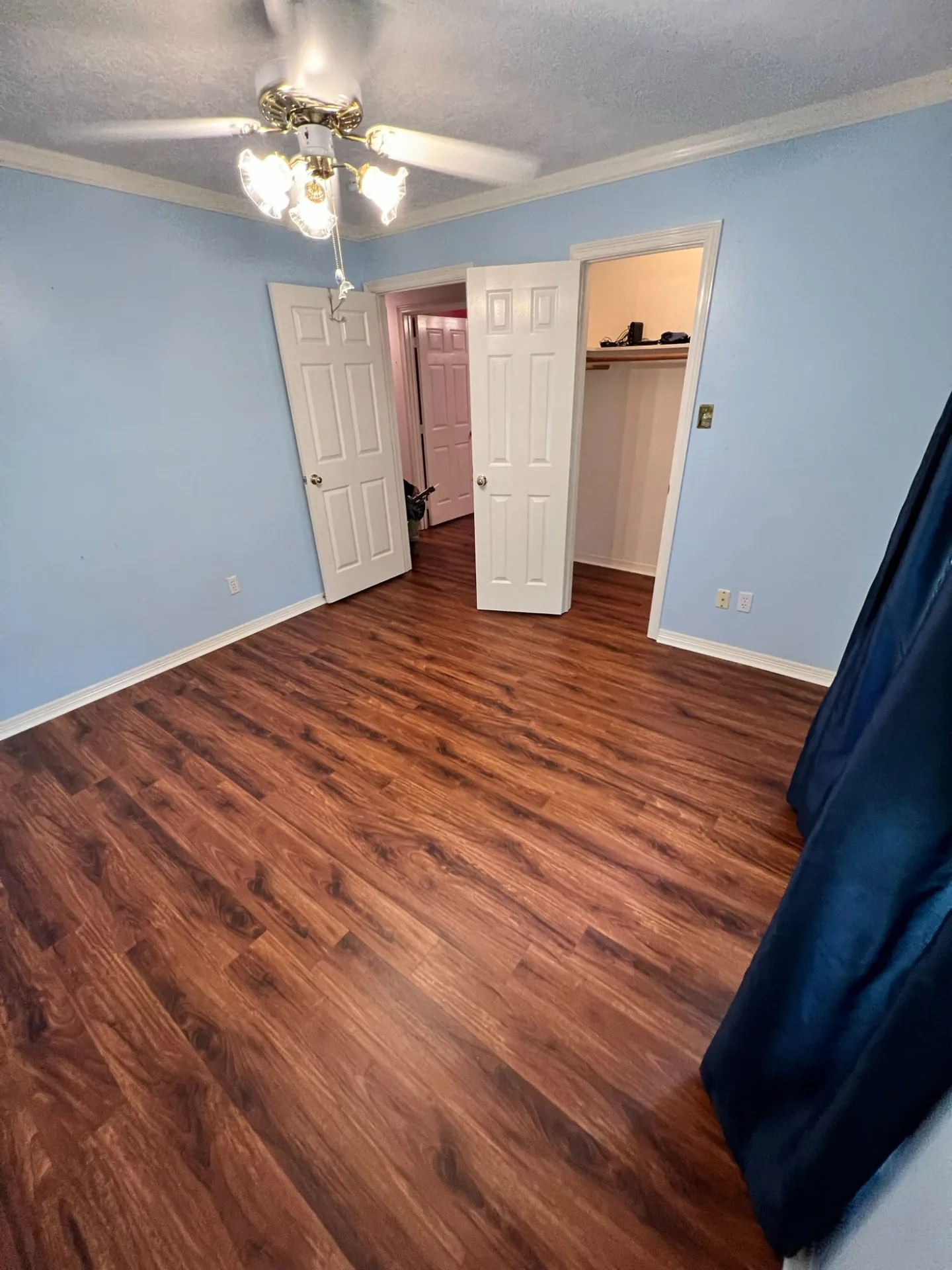 A bedroom finished in dark walnut vinyl plank with white doors and baseboards